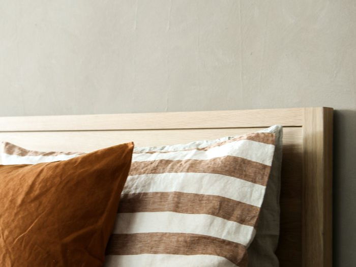 Close-up of linen cushions and bedding in warm neutral tones.